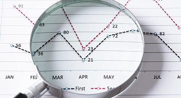 Magnifing glass and documents with analytics data lying on table 1
