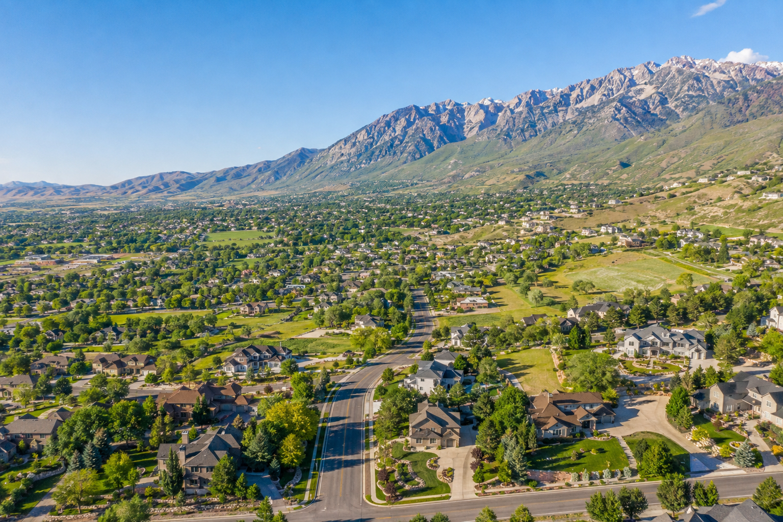 Panoramic view of Alpine, Utah, showing residential communities, open spaces, and mountain ranges across the valley.