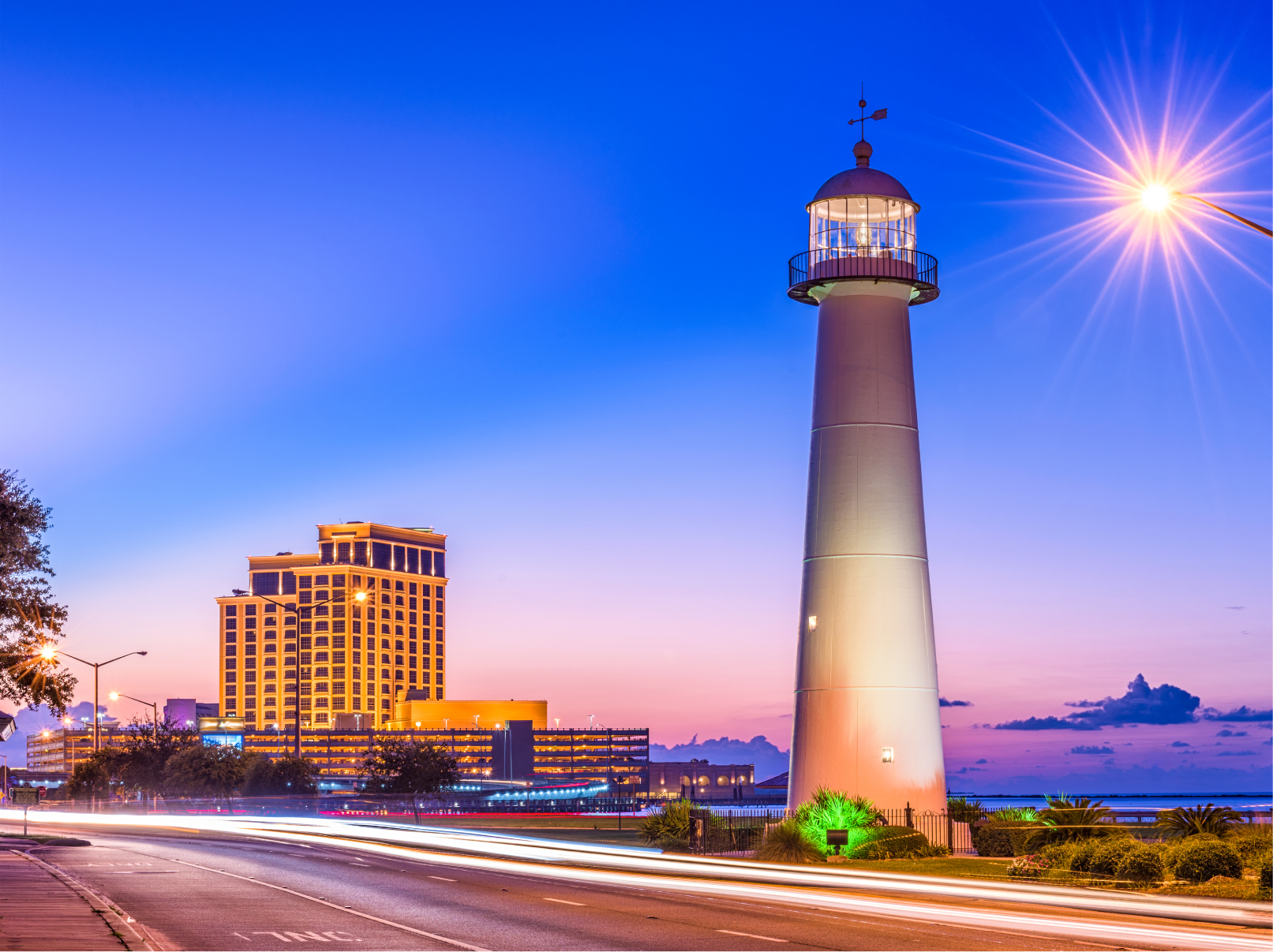 Biloxi, Mississippi lighthouse at dusk with illuminated casino in the background and light trails along the road