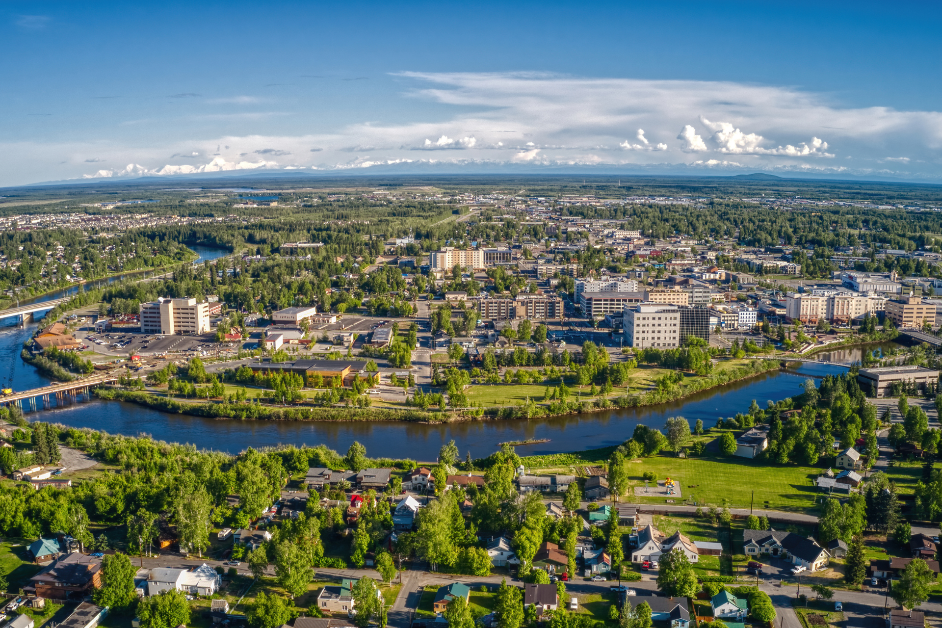 Aerial view of Fairbanks, Alaska, showing the Chena River winding through the city with surrounding neighborhoods, businesses, and green landscapes.