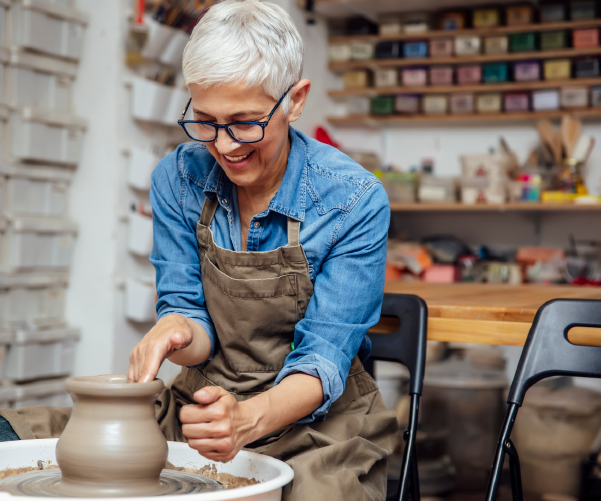 Senior woman spinning pottery and smiling Senior woman spinning pottery and smiling
